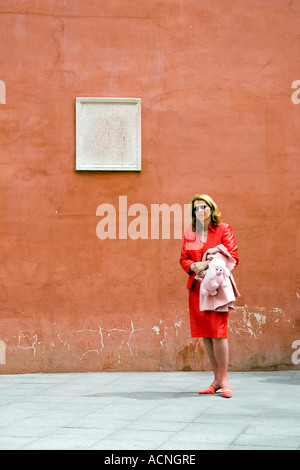 Donna in rosso nella parte anteriore di una parete arancione, Siviglia, Spagna Foto Stock