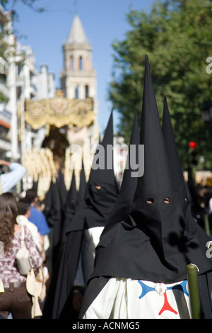 I penitenti De La Trinidad di fraternità durante il sabato di Pasqua processioni. Vergine sul suo galleggiare su sfondo, Siviglia. Foto Stock