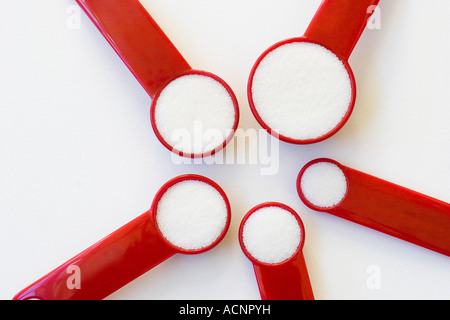 Rosso Cinque misurini riempita con sale disposte in cerchio su uno sfondo bianco Foto Stock