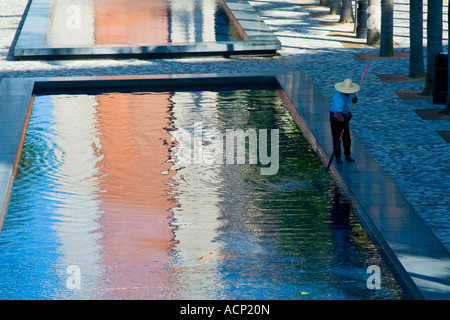 La donna Pulisce la piscina di acqua e Refelection della vecchia torre dell orologio al Centro Culturale di Hong Kong Hong Kong Foto Stock