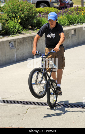 Ragazzo adolescente fare acrobazie sul suo bmx bike Foto Stock