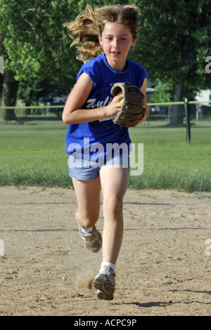 Giovane ragazza che corre verso la telecamera a una pratica di softball gioco. Foto Stock