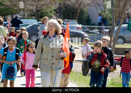 Grado insegnante di scuola gli studenti a piedi ad aspettare autobus e automobili i genitori. Horace Mann scuola elementare St Paul Minnesota USA Foto Stock