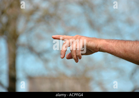 La mano e le dita che puntano verso sinistra di cowboy che cerca il bestiame sul ranch durante il giro su di vitelli per marcare a caldo Foto Stock