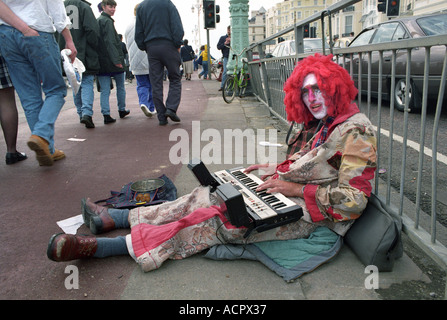 Un animatore di strada vestito come un clown di fronte al mare a Brighton SUSSEX REGNO UNITO Foto Stock