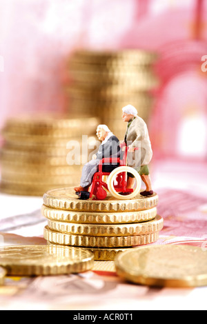Figurine in sedia a rotelle sulla pila di monete, vista laterale Foto Stock