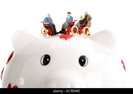 Figurina seduto su una sedia a rotelle sul porcellino salvadanaio Foto Stock