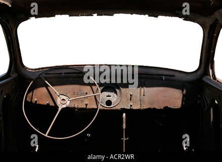All'interno di un vecchio arrugginito relitto di una vettura che mostra il cruscotto e il volante con il parabrezza Isolato bianco. Foto Stock