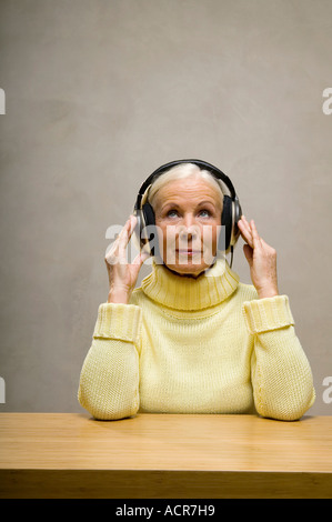 Senior donna che indossa le cuffie, guardando in alto, close-up Foto Stock