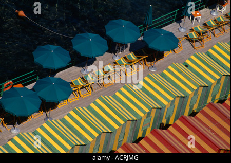 L'Italia, Campania, Sorrento. Vista su colorate, striped beach capanne, strisce di sedie a sdraio e verde ombrelloni su legno decking. Foto Stock