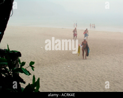 Lucertole da mare e nuotatori eseguito da spiaggia cercando rifugio in improvviso acquazzone tropicale Ko Pha Ngan isola della Thailandia Foto Stock