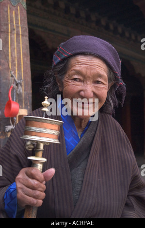 Un anziano tibetano pellegrino gira la sua ruota di preghiera presso il tempio del Jokhang Lhasa Tibet Foto Stock