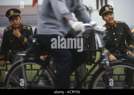 Una corsa in bicicletta attraverso due soldati in piazza Tiananmen Pechino CINA Foto Stock