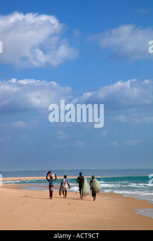 Un gruppo di pescatori locali passeggiando lungo la spiaggia che porta un net Barra Inhambane Provincia Mozambico Foto Stock