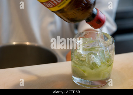 Un barman versando cachaça in un vetro a rendere un drink di Caipirinha Brasile del cocktail nazionali Foto Stock