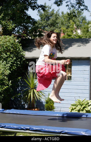 Ragazza sul trampolino nella zona suburbana di giardino in estate Foto Stock