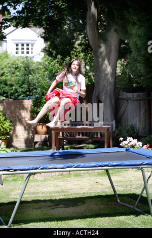 Ragazza sul trampolino nella zona suburbana di giardino in estate Foto Stock