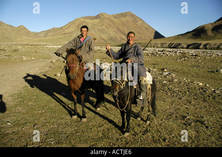 Nomads due giovani uomini sono seduti sulle loro cavalli vestiti di cappotti tradizionali con le pistole nella steppa Mongola Kharkhiraa Foto Stock