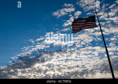 Una bandiera americana parzialmente stagliano contro un cielo blu con nuvole bianche a Kearney, Nebraska, Stati Uniti d'America. Foto Stock