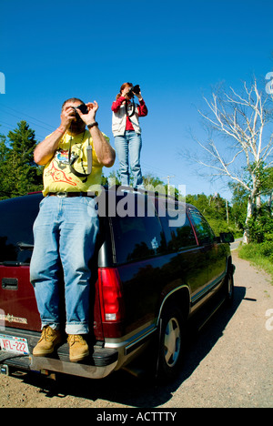 Due fotografi maschi e una femmina di scattare foto mentre si sta in piedi sul tetto di un carrello di prelievo Foto Stock