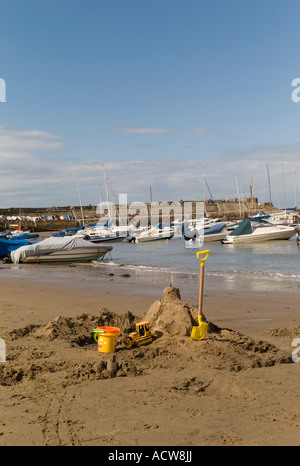 Un bambino di sandcastle benna e forcella sul New Quay beach Cardigan Bay west wales con barche ormeggiate nel porto dietro estate Foto Stock