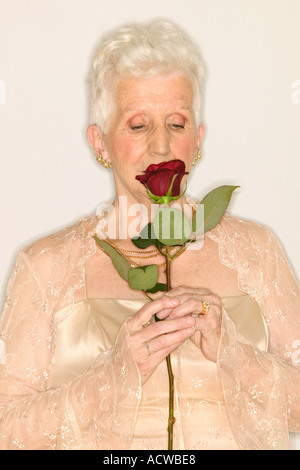 Senior donna lo sniffing rose Foto Stock