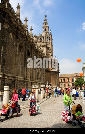 Donne e bambini in abito tradizionale al di fuori del grande cattedrale gotica di Siviglia durante la Feria Fiesta Foto Stock