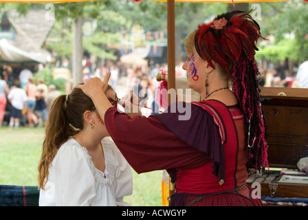 Una faccia pittore Lady è la pittura la faccia di una bambina Foto Stock