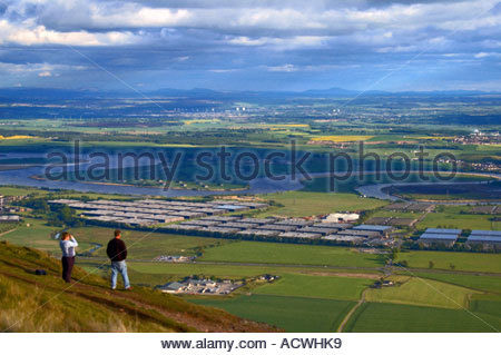 Due escursionisti che si affacciano sulla Forth Valley e sul fiume che si estende dalla cima della collina di Dumyat, Scozia Foto Stock