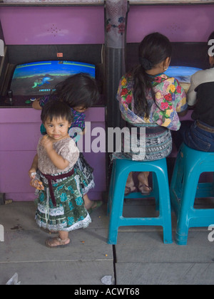 Indigenously vestito kids play video giochi rendendo un contrasto di international vs local Foto Stock