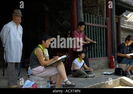 Arte cinese gli studenti a lavorare nella grande moschea di Xian con il loro insegnante cercando su Foto Stock