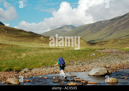 Persona che indossa overboots in plastica per mantenere asciutta mentre attraversando il fiume Meig in Gleann Fhiodhaig, Invernesshire, Scotland, Regno Unito Foto Stock