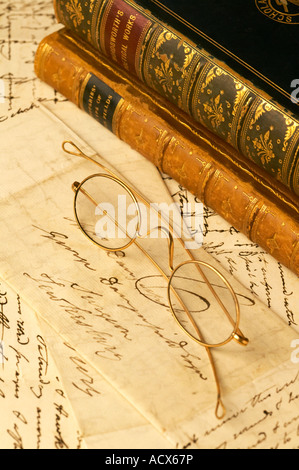 Oro antico vetri bordati di occhiali in appoggio sulle lettere scritte a mano con pelle di libri rilegati Foto Stock