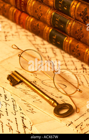 Oro antico vetri bordati di occhiali in appoggio sulle lettere scritte a mano con pelle di libri rilegati e chiave in ottone Foto Stock