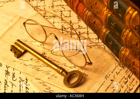 Oro antico vetri bordati di occhiali in appoggio sulle lettere scritte a mano con pelle di libri rilegati e chiave in ottone Foto Stock