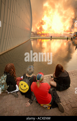 Le persone accanto al museo di arte contemporanea a guardare la masterizzazione vecchia ferrovia magazzini vicino alla principale stazione ferroviaria, Helsinki, Finlandia, UE Foto Stock