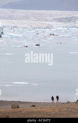 Due persone sulla riva del Jokulsarlon laguna glaciale, ghiacciaio Vatnajokull in Islanda Foto Stock