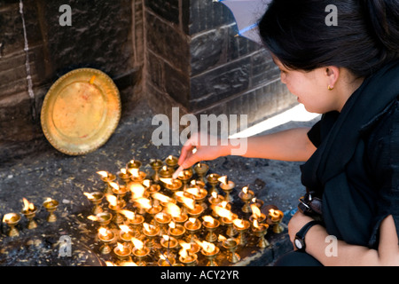 Il nepalese donna offerta di illuminazione di lampade a burro.Swayambhunath Stupa.Kathmandu.Nepal Foto Stock