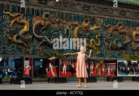 Una bambina gioca badminton nella parte anteriore del nove la parete del drago in Pingyao Shanxi in Cina 7 Giu 2007 Foto Stock