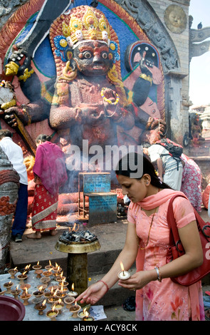 Donna illuminazione di lampade a burro per Kala Bhairab Dio.Durbar Square.Kathmandu.Nepal Foto Stock