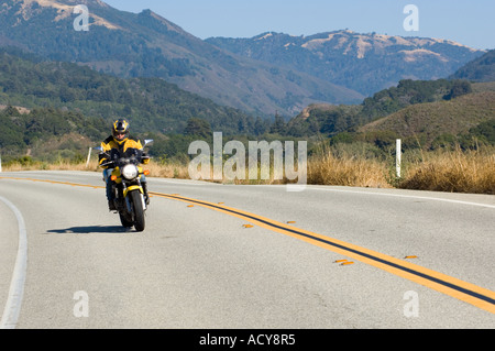 Unica femmina matura motociclista rides motocicletta lungo la Pacific Coast Highway 1 a nord di Big Sur, California Foto Stock
