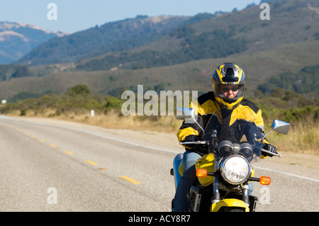 Unica femmina matura motociclista rides motocicletta lungo la Pacific Coast Highway 1 a nord di Big Sur, California Foto Stock