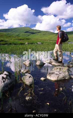 Estate passeggiate in collina nel Galloway Forest Park walker a Loch Neldricken con Merrick e nuvole dietro Galloway Scotland Regno Unito Foto Stock