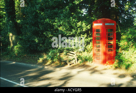 Il vecchio telefono rosso box lungo la strada tra alberi da qualche parte in Kent England Regno Unito Foto Stock