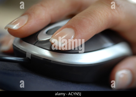 Womans mano utilizzando un mouse con rotella di scorrimento in un ufficio Foto Stock