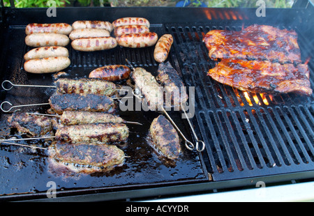 Barbecue grigliate di carne alimentare essendo cotti su un barbecue a gas salsicce di maiale Agnello e menta spiedini su spiedini Foto Stock