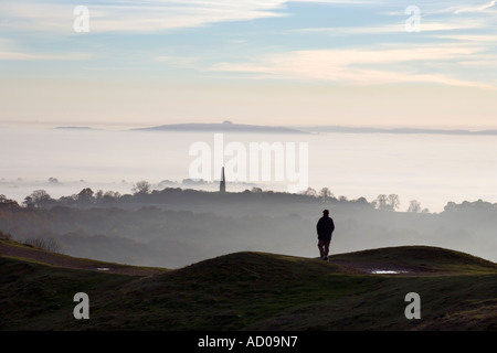 Un viandante sulla sommità della Malvern Hills in WORCESTERSHIRE REGNO UNITO al di sopra di fitta nebbia che copre la campagna circostante Foto Stock