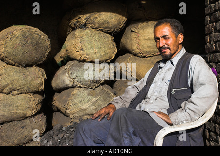 Afghanistan, centro di Kabul, Bazaar, negoziante siede in cattedra nel negozio di carbone Foto Stock