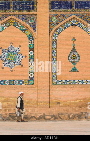 Afghanistan, Herat, uomo che porta il bollitore passeggiate passato venerdì moschea o Masjet-eJam Foto Stock