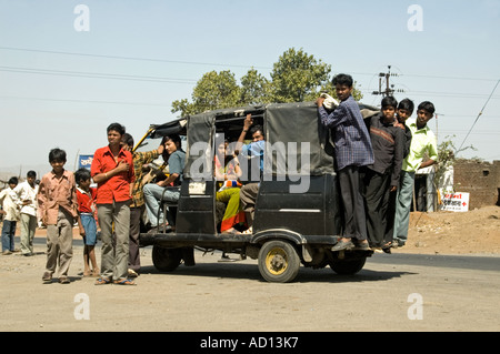 Vista orizzontale di un gruppo di bambini Indiani in cramming un travagliato vecchi rickshaw parcheggiata sul lato della strada Foto Stock